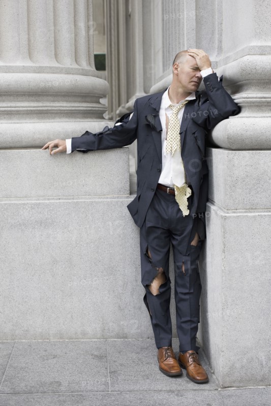 Businessman wearing torn clothing outside office building, San Francisco, California, USA. Photographe : PT Images