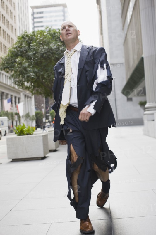 Businessman wearing torn clothing, walking in street, San Francisco, California, USA. Photographe : PT Images