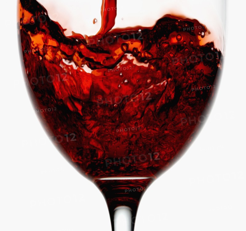 Red wine being poured into wineglass, close-up. Photographe : Joe Clark