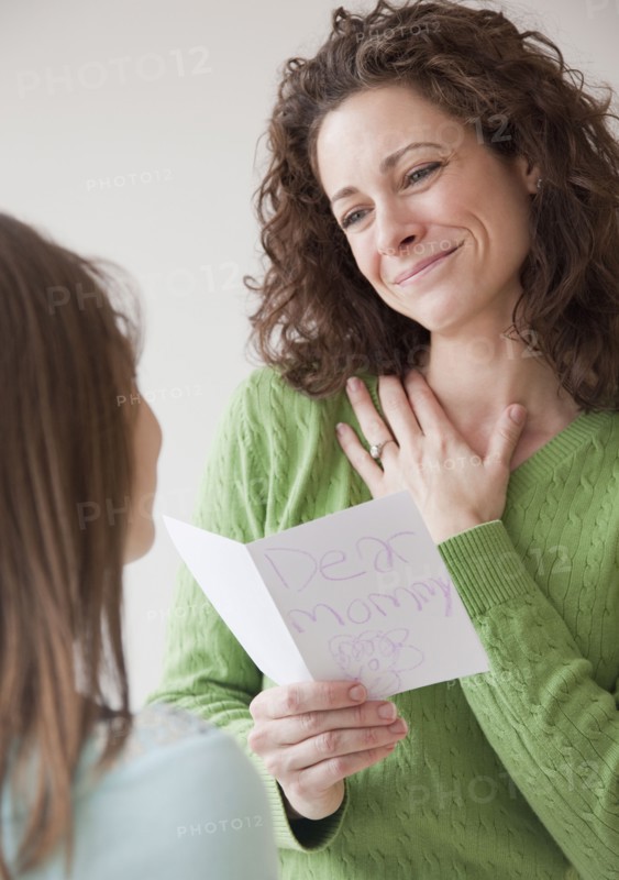 Mother receiving greeting card on mother's day from daughter (10-12 years). Photographe : Jamie Grill