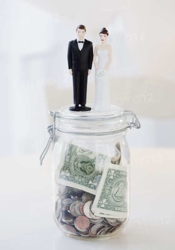 Bride and groom cake toppers on jar of money. Photographe : Jamie Grill