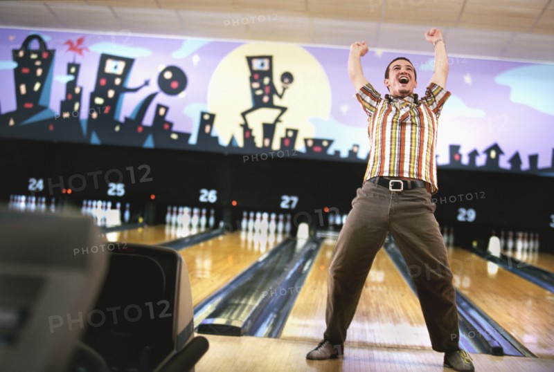 Man standing in front of bowling alley and cheering. Photographe : Stewart Cohen