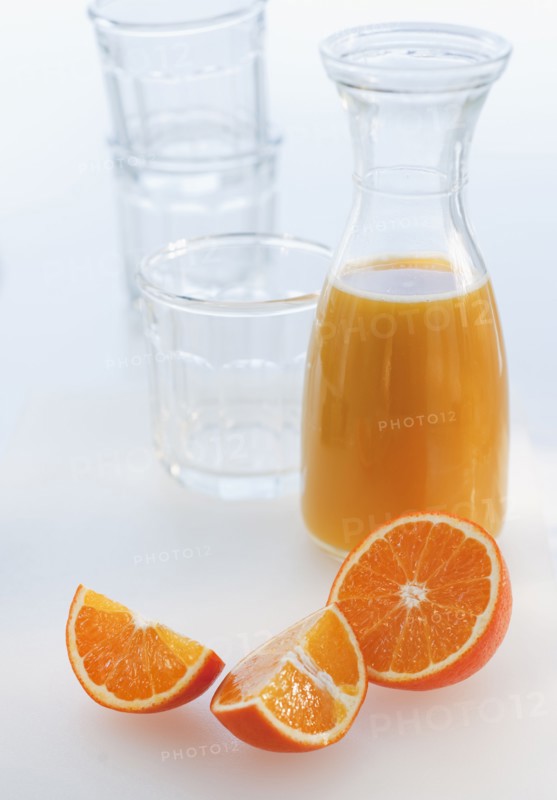 Fresh orange juice in decanter with oranges slices, studio shot.