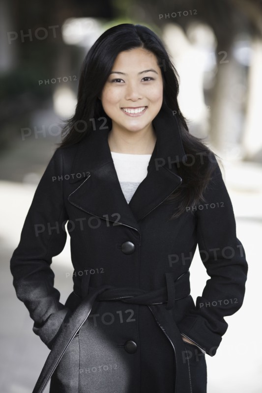 Portrait of young woman standing in street. Photographe : PT Images