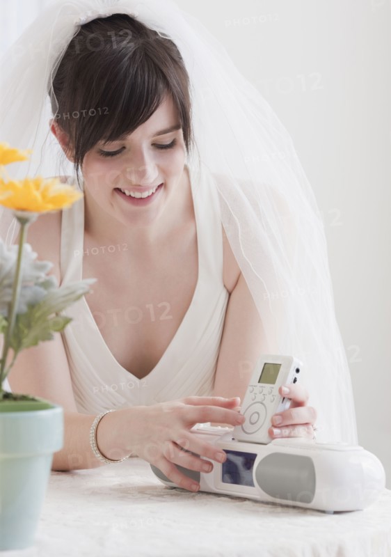 Bride holding speakers of stereo, studio shot. Photographe : Jamie Grill