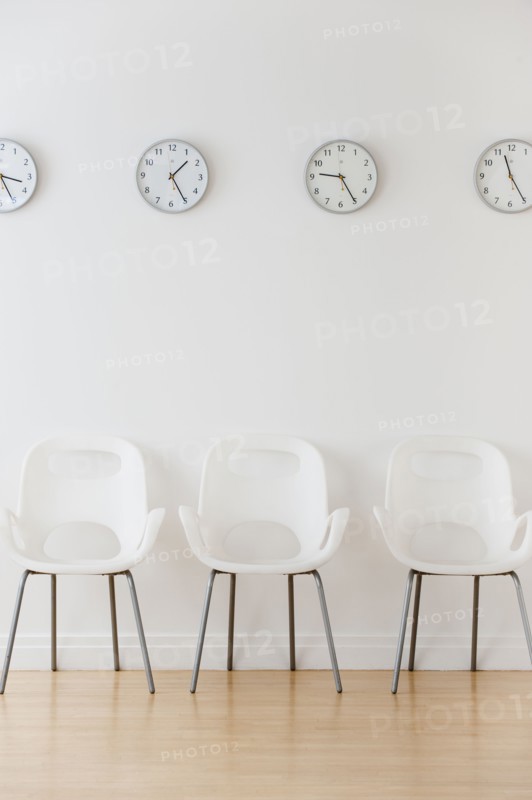 Row of chairs in waiting room under clocks displaying time zones.