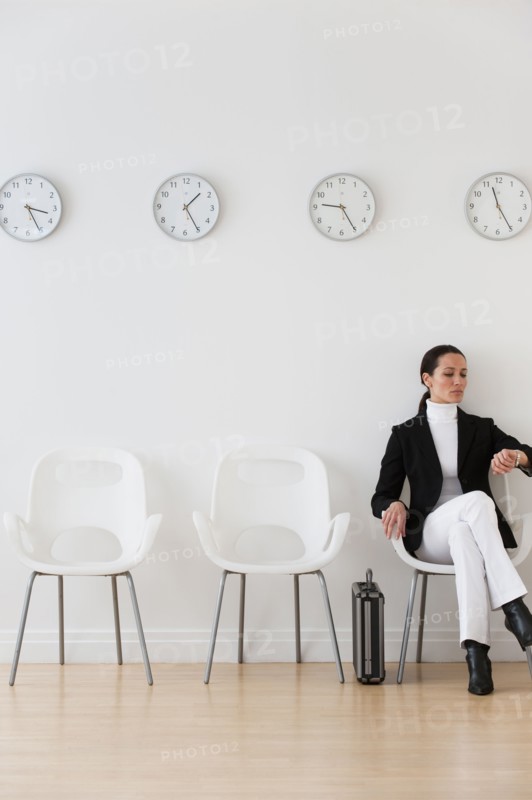 Businesswoman looking at wrist watch in waiting room.