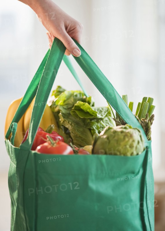 Woman holding grocery bag, close-up.