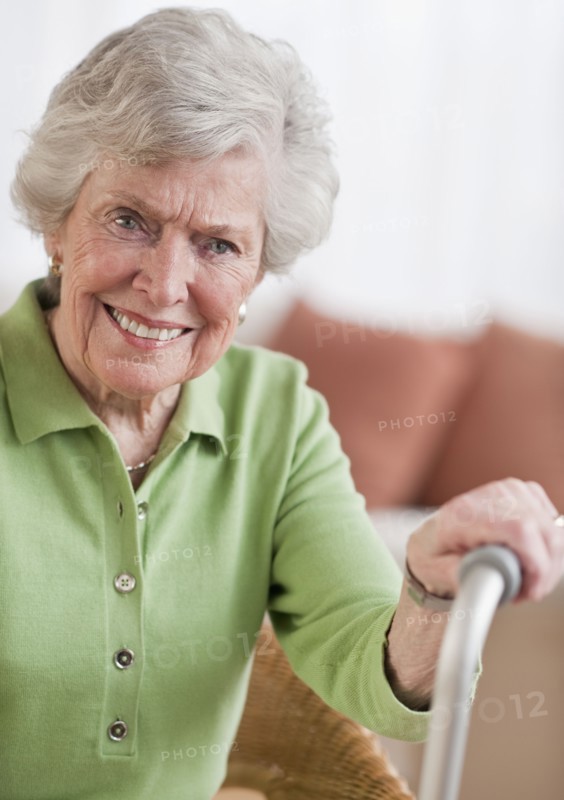 Senior woman sitting and holding walking stick.