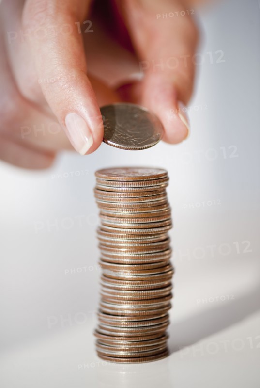 Close-up of woman's hand stacking coins.