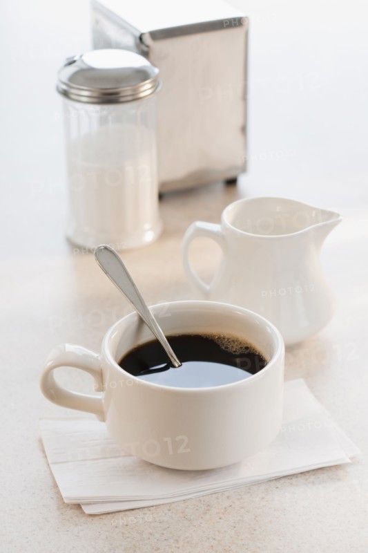 Cup of coffee with milk and sugar on table.