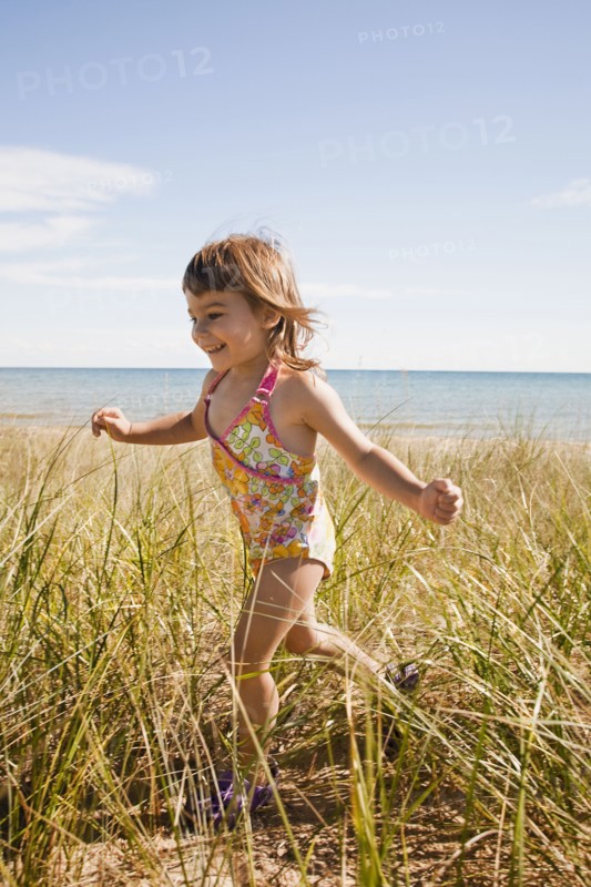 Beaver Island, Girl running in grass on beach, Beaver Island, Michigan, USA. Photographe : Shawn O'Connor