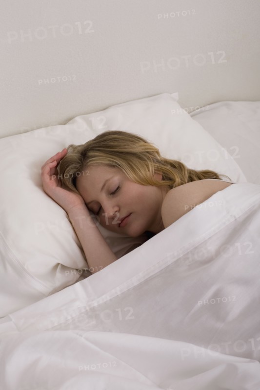 Young woman sleeping in bed. Photographe : David Engelhardt
