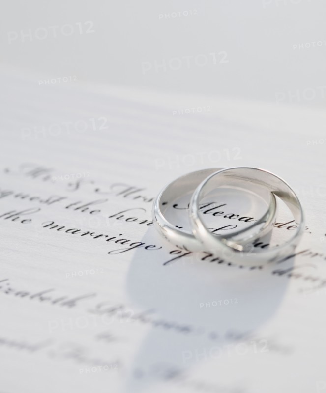 Two wedding rings on marriage certificate, studio shot. Photographe : Jamie Grill