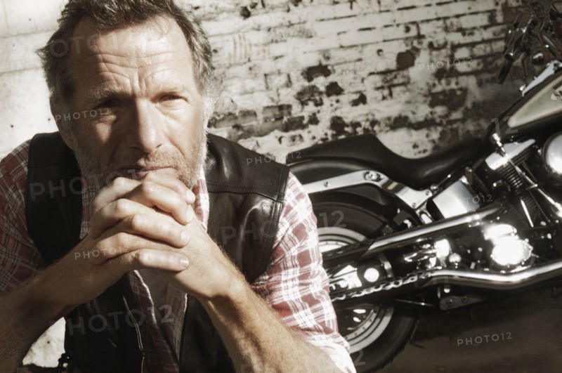 Mature man in front of motorcycle. Photographe : Stewart Cohen