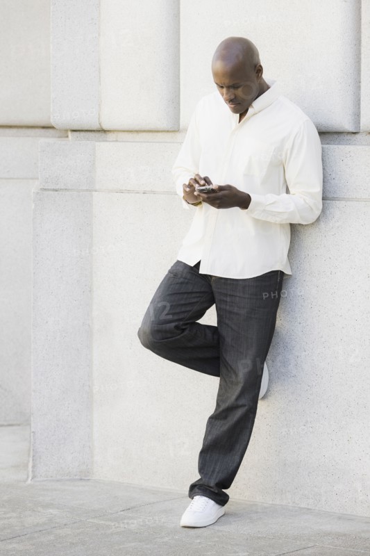 Man text messaging outside office building. Photographe : PT Images