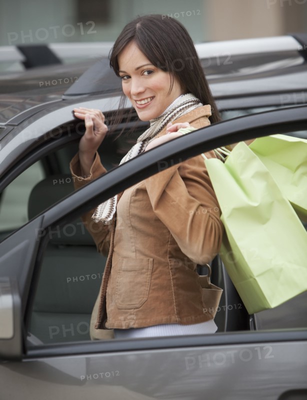 Portrait of woman getting into car with shopping bags.
