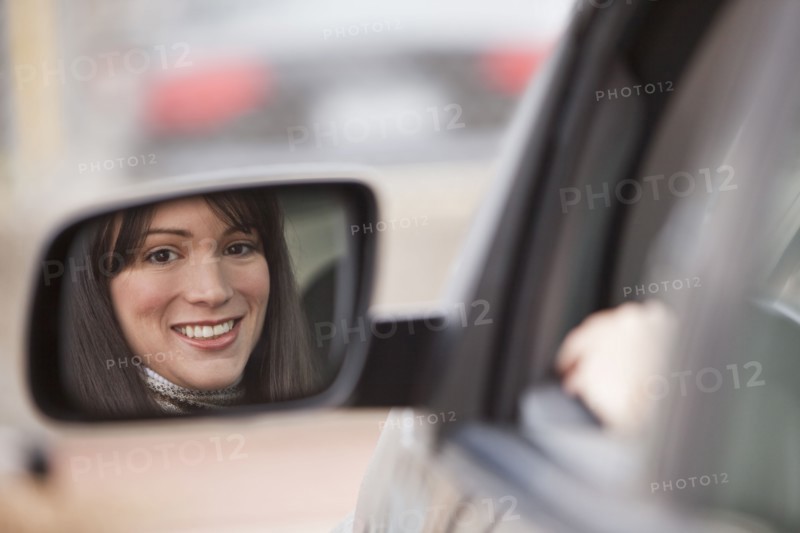 Reflection of woman in side view mirror.