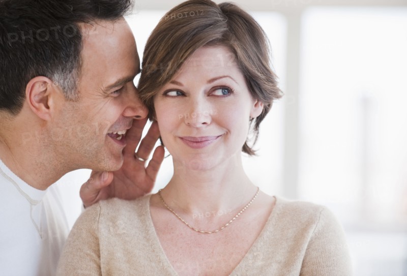 Man whispering to woman's ear.