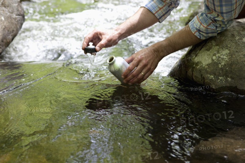 A man with a reusable water bottle in the woods