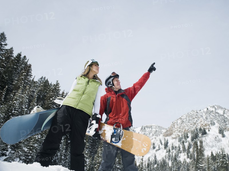 Two snowboarders pointing at sky