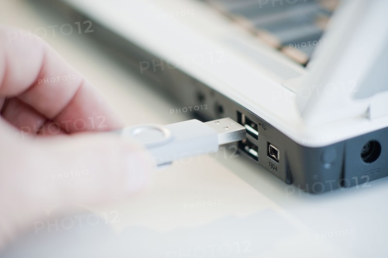 A hand plugging in a universal serial bus.