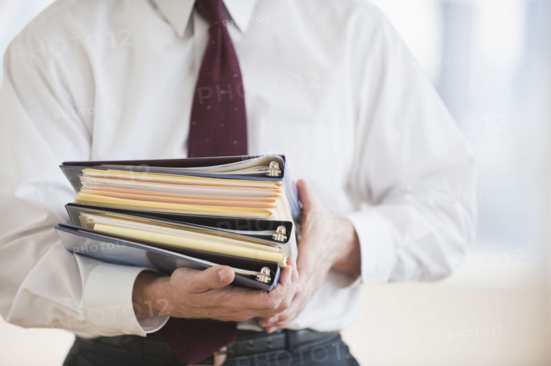 Businessman carrying binders.