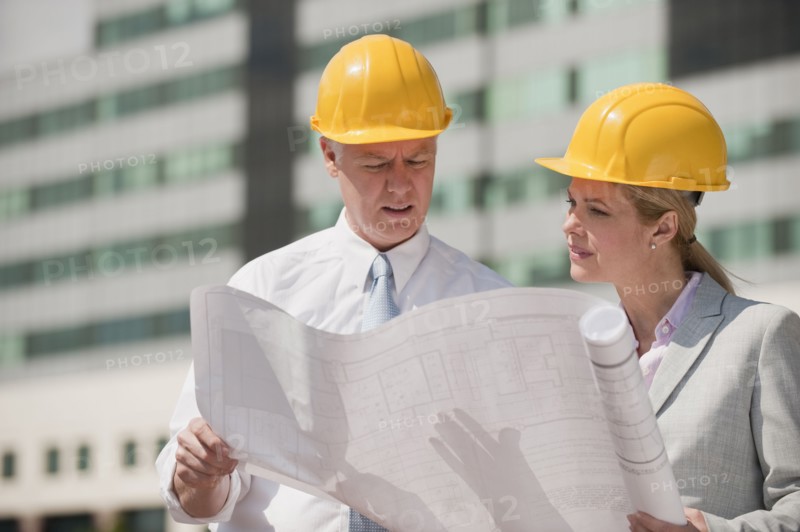 Two architects holding plans outdoors.