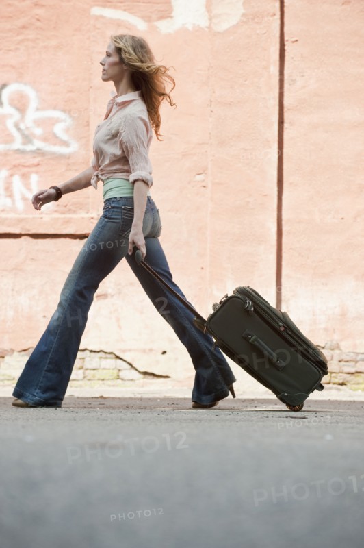 A woman walking with a suitcase.