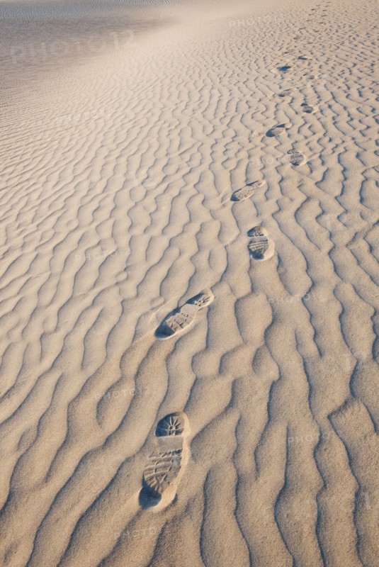 Sand dunes in the desert with footprints.