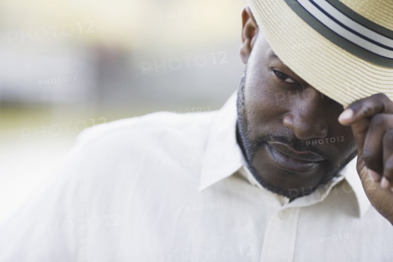 A man outdoors fixing his hat