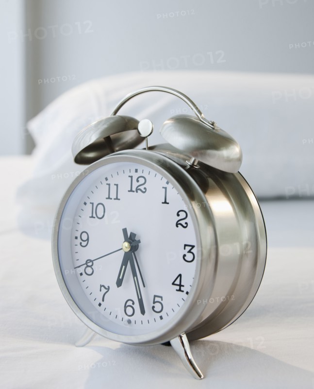 An alarm clock on a bed