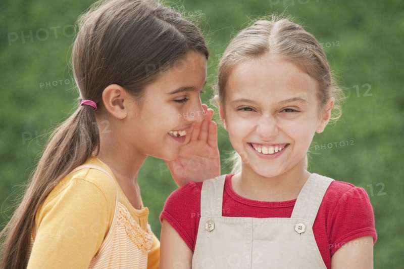 Two girl friends whispering.