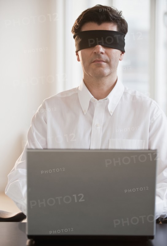 Businessman using laptop while blindfolded.