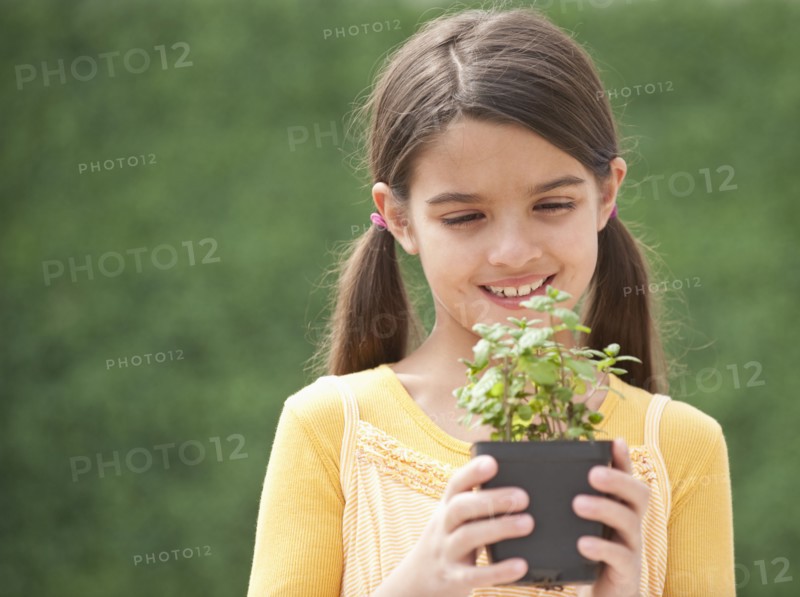 A young girl holding a plant.
