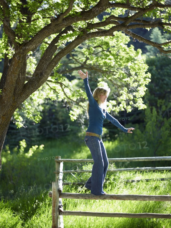 Young woman balancing on fence