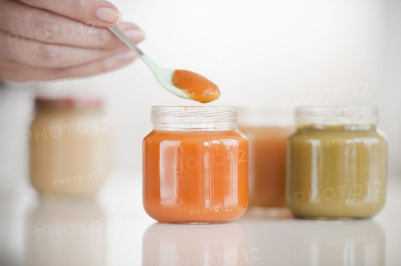 Hand spooning baby food.