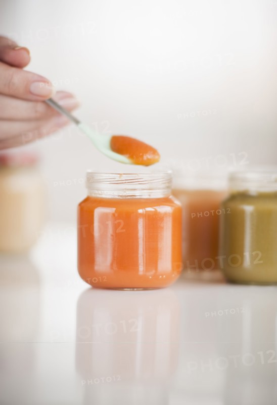 Hand spooning baby food.