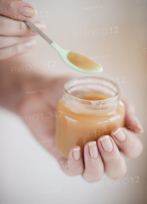 Hand spooning baby food.