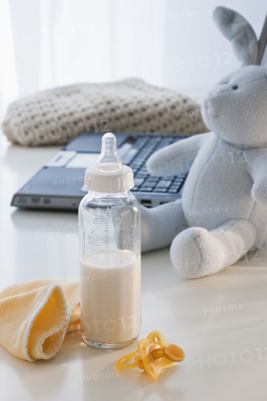 Baby bottle beside laptop.
