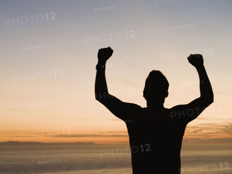 Silhouette of man raising arms