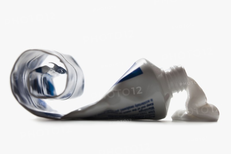 Half empty toothpaste tube spilling