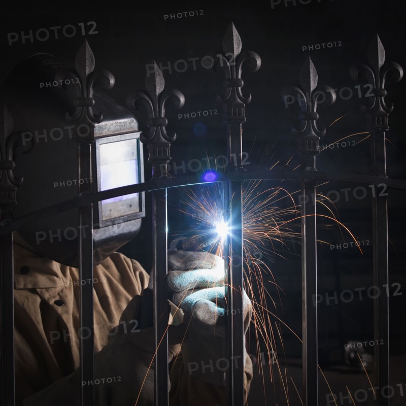 Steel worker welding a fence