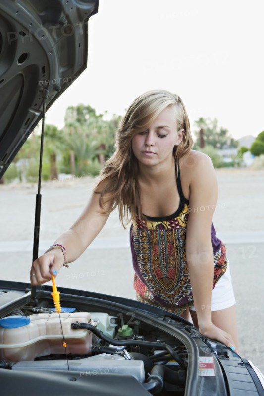 Woman checking car's oil