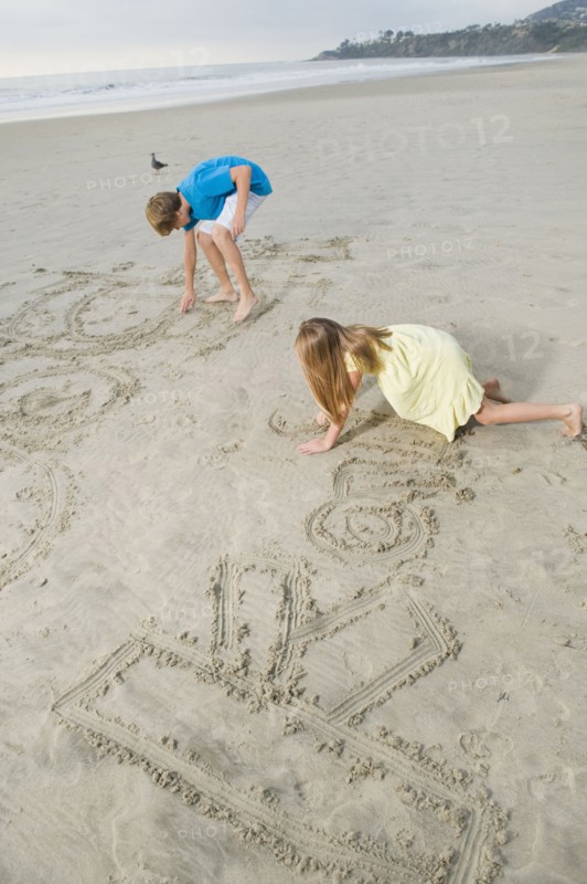 Children writing on beach