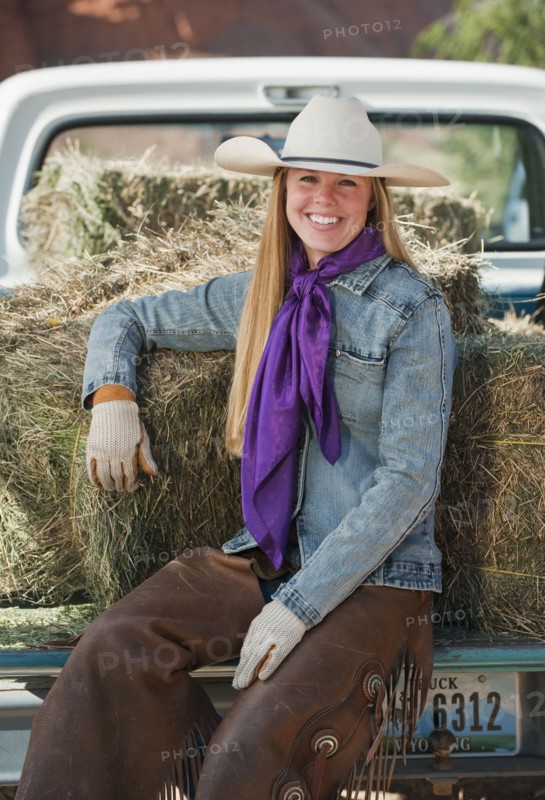 Cowgirl sitting on back of truck.