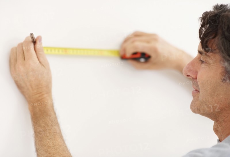 Carpenter measuring wall. Photographer: momentimages