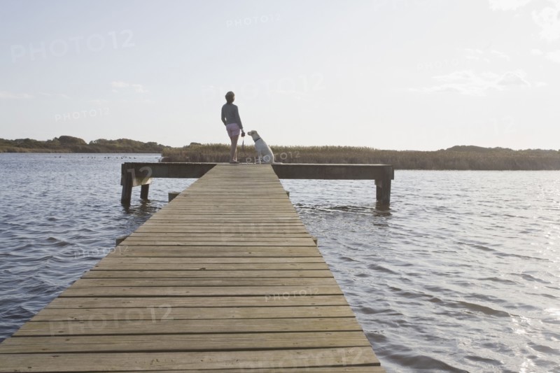 Woman and dog on pier. Photographer: Chris Hackett