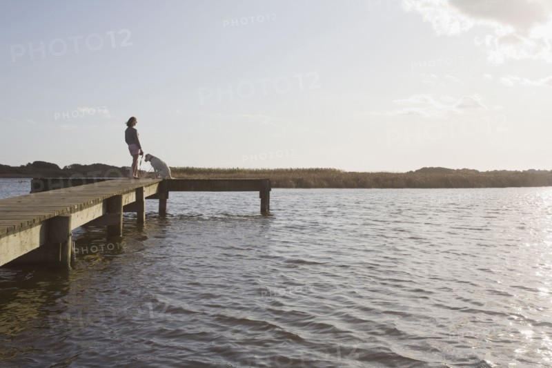 Woman and dog on pier. Photographer: Chris Hackett