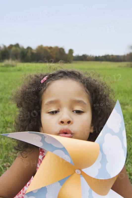 Young girl blowing toy windmill. Photographer: Pauline St.Denis